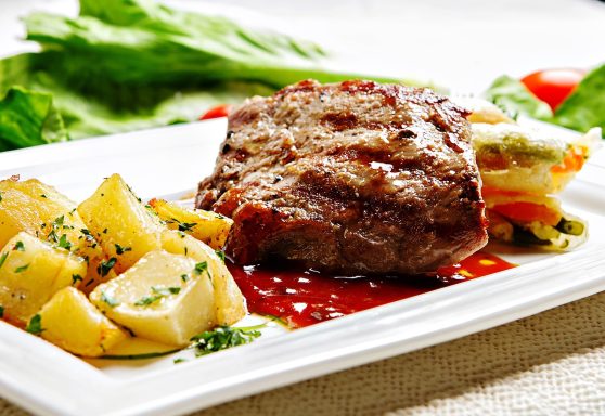 Filete jugoso , acompañado de papas y una guarnición de verduras frescas.