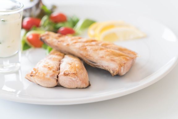 PESCADO PLANCHA con guarnición de ensalada y rodajas de limón.